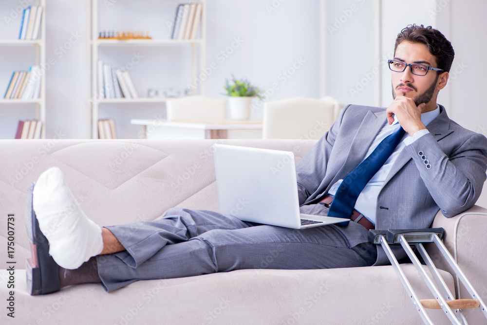 Businessman with crutches and broken leg at home working