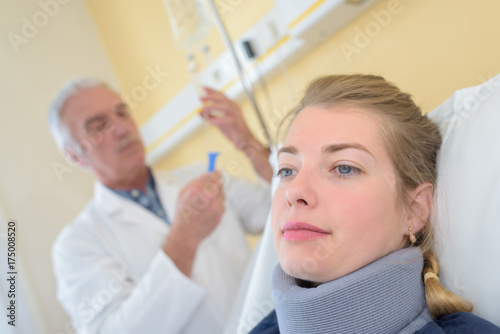Doctor tending to drip, patient wearing neck brace