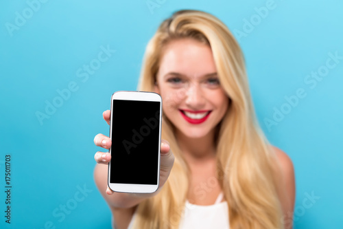 Young woman holding out a cellphone in her hand