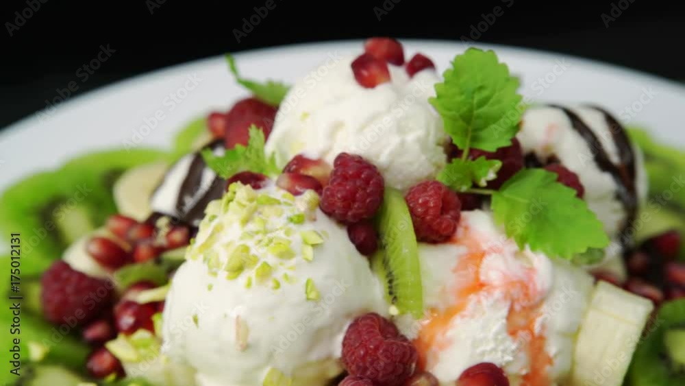 ice cream dessert with fruits, berries chocolate and strawberry sauce rotating on a plate. ice cream dessert with fruits, berries chocolate and strawberry sauce rotating on a plate.