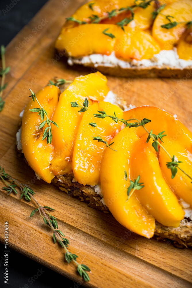 Bread with ricotta cheese and grilled peaches on the rustic background. Shallow depth of field. Selective focus.