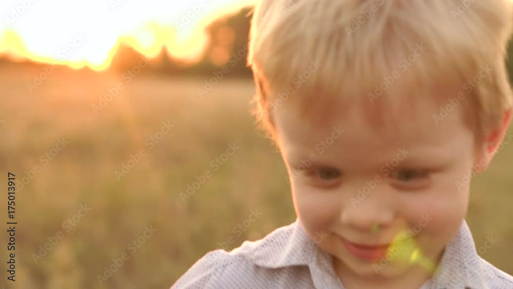 Close-up face happy funny little boy in a field at sunset. Slow motion. Close-up face happy funny little boy in a field at sunset. Slow motion.