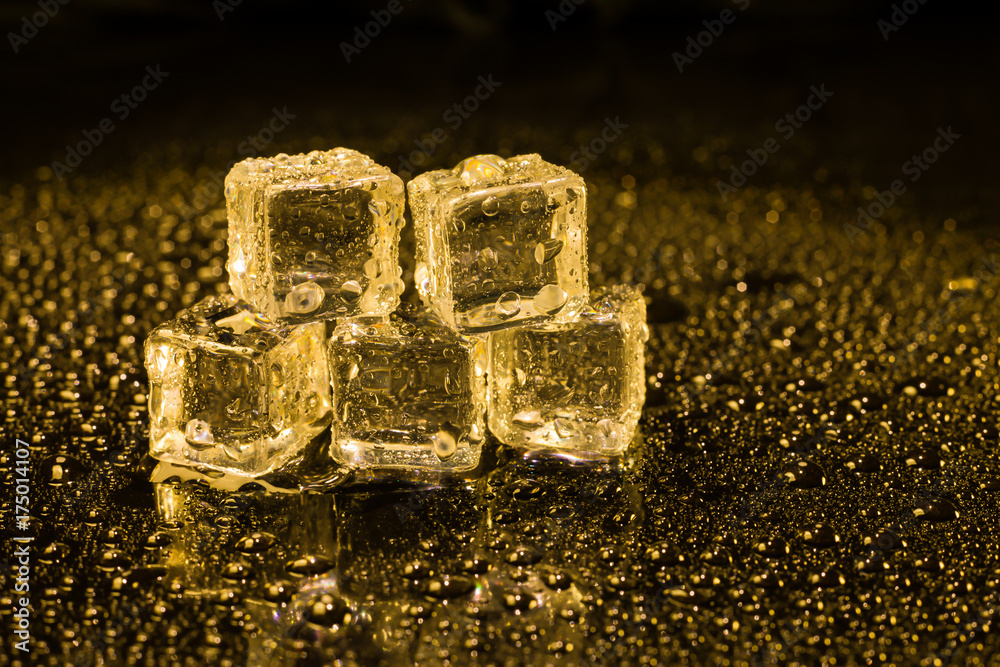 Ice cubes in yellow light on black wet table. Ice cubes in yellow light on black wet table.
