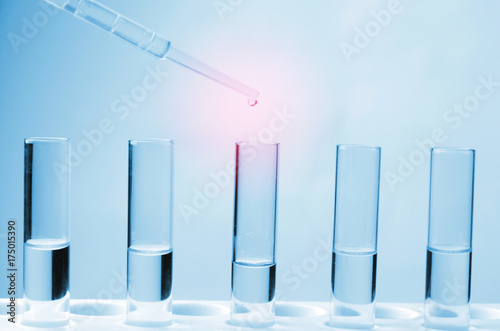 dropping chemical liquid to test tube, blue color tone, laboratory, science, chemical and medical research concept, soft and selective focus