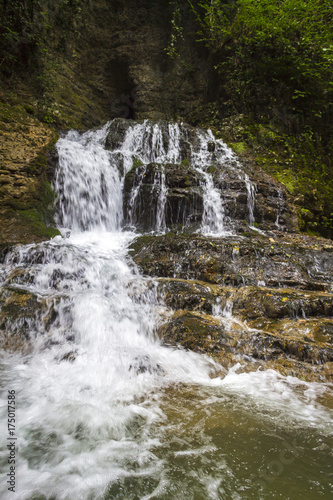 Fototapeta Naklejka Na Ścianę i Meble -  Beautiful small waterfall in wild overgrown places.