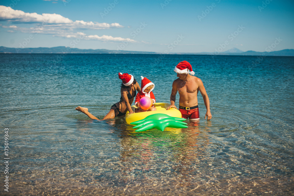 Family Christmas. Christmas photo. Santa hats. Sea background. Child. Childhood. Love. Travel. 