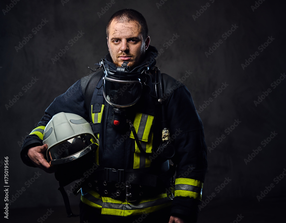 Naklejka premium Firefighter dressed in uniform holds safety helmet.