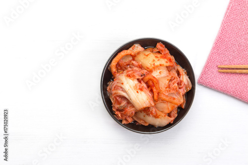 kimchi in ceramic dish on white wooden board with copy space, top view. healthy food concept.