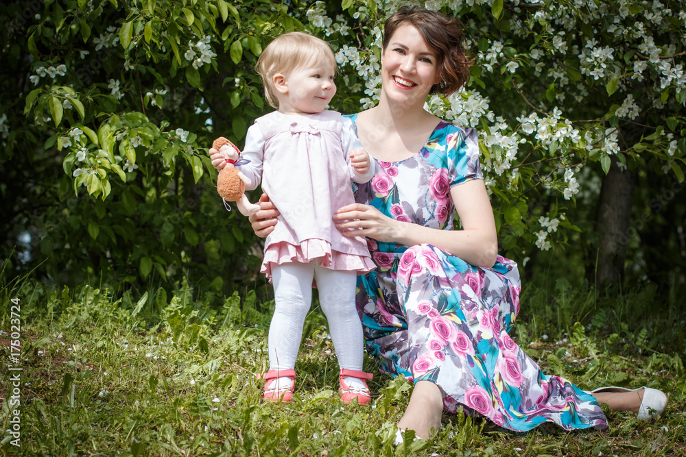 Mother and daughter have fun in the park and apple tree with white flowers Mother and daughter have fun in the park and apple tree with white flowers