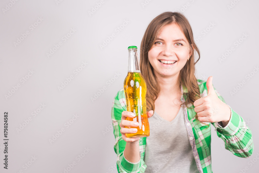 Beautiful woman holding a bottle of beer and showing thumbs up. Background with copy space Beautiful woman holding a bottle of beer and showing thumbs up. Background with copy space