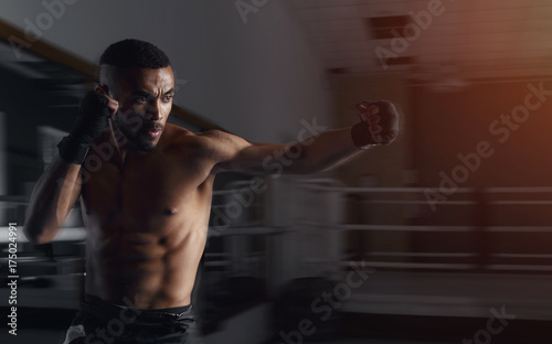 Boxing man. African american male boxer. Side view, muscular man boxing on background boxing gym. Afro american boxer male practicing boxing, sparring in driving dynamics.