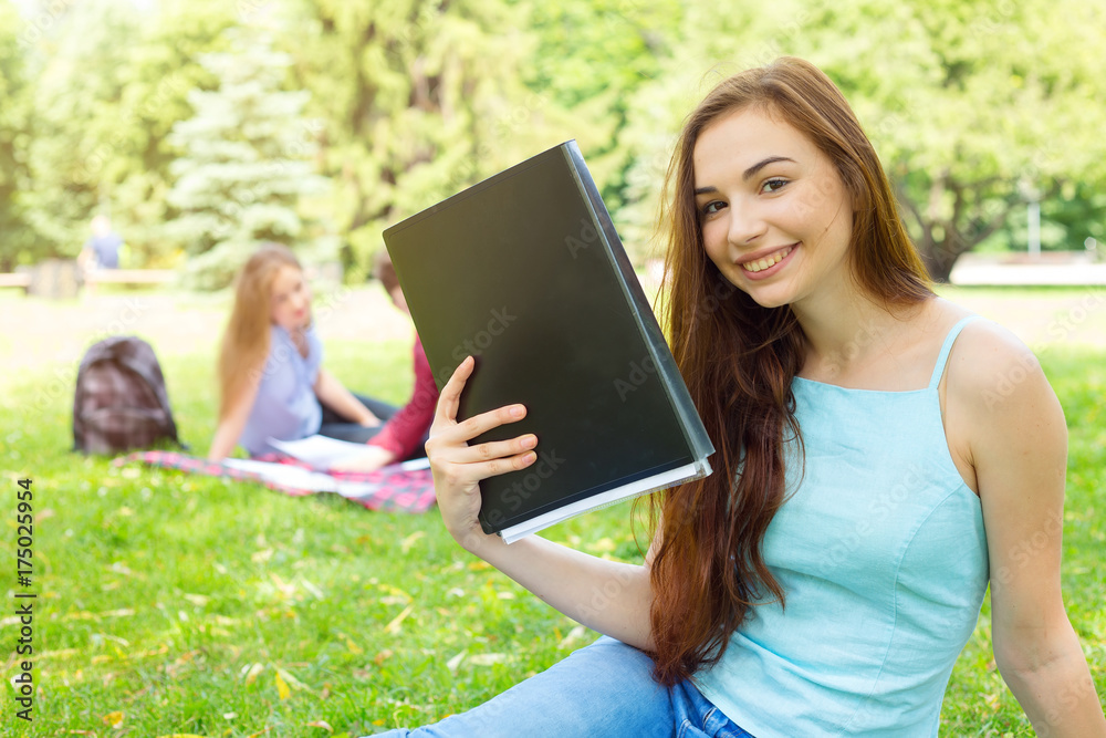 Obraz premium Young female student holding a folder and shows the tasks for training. Student weekdays. Happy woman.