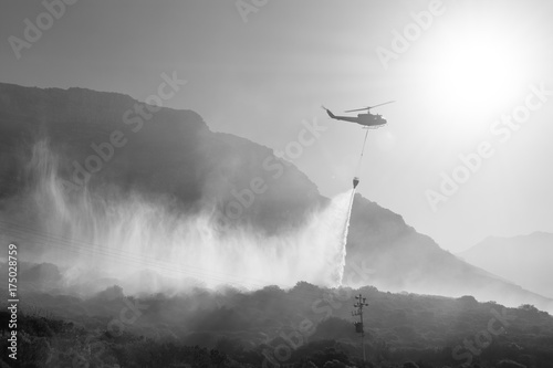 A firefighting Bell Huey helicopter dumps water onto a bush fire in Cape Town, South Africa.