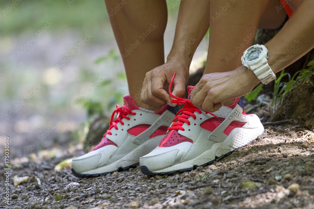 Female hands tying shoelace on running shoes before practice