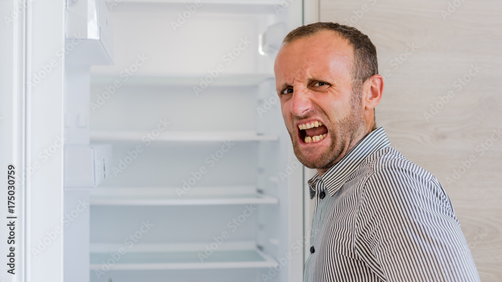 Empty fridge with a desperate hungry man Empty fridge with a desperate hungry man