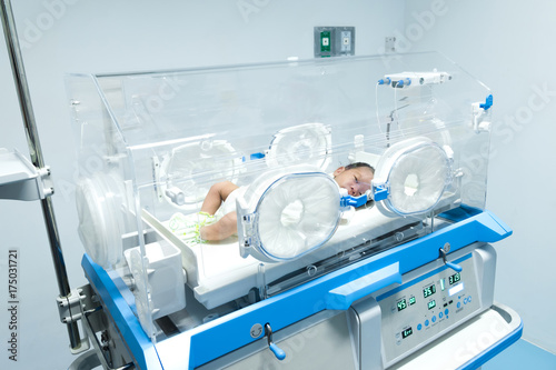 Infant in incubator machine maintain healthy environment for newborn premature sick babies neonatal intensive care unit. photo