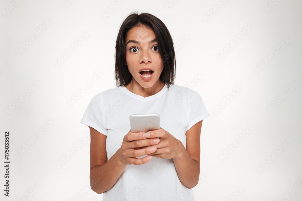 Portrait of a shocked bunette woman holding mobile phone Portrait of a shocked bunette woman holding mobile phone