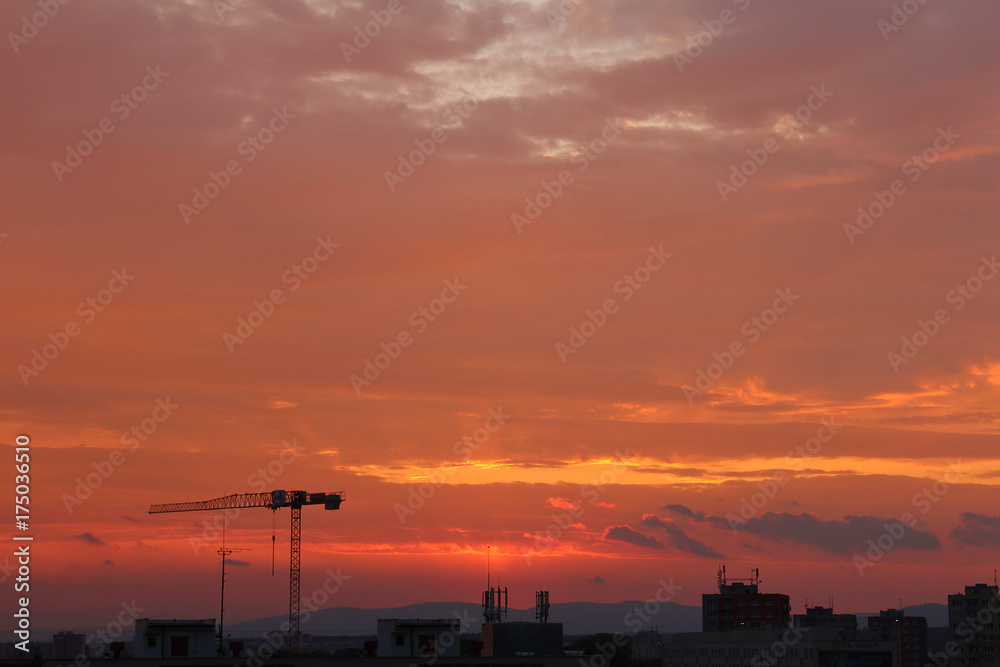 Ceske Budejovice with crane silhouette in orange sunset sky