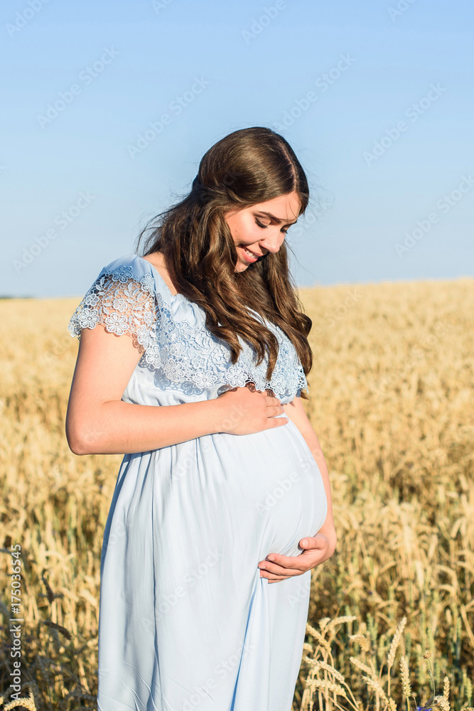 Outdoor portrait of unrecognizable young pregnant woman in the field. beautiful pregnant woman with big belly relaxing in the summer nature meadow Outdoor portrait of unrecognizable young pregnant woman in the field. beautiful pregnant woman with big belly relaxing in the summer nature meadow