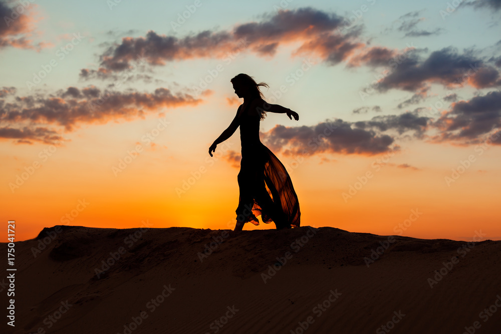 Fototapeta premium Silhouette of a woman during a dance at sunset.