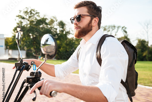 Side view of Cool bearded man in sunglasses with backpack