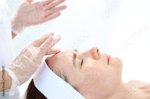  Relaksacyjny masaż twarzy. Kobieta w salonie kosmetycznym podczas zabiegu masażu twarzy.