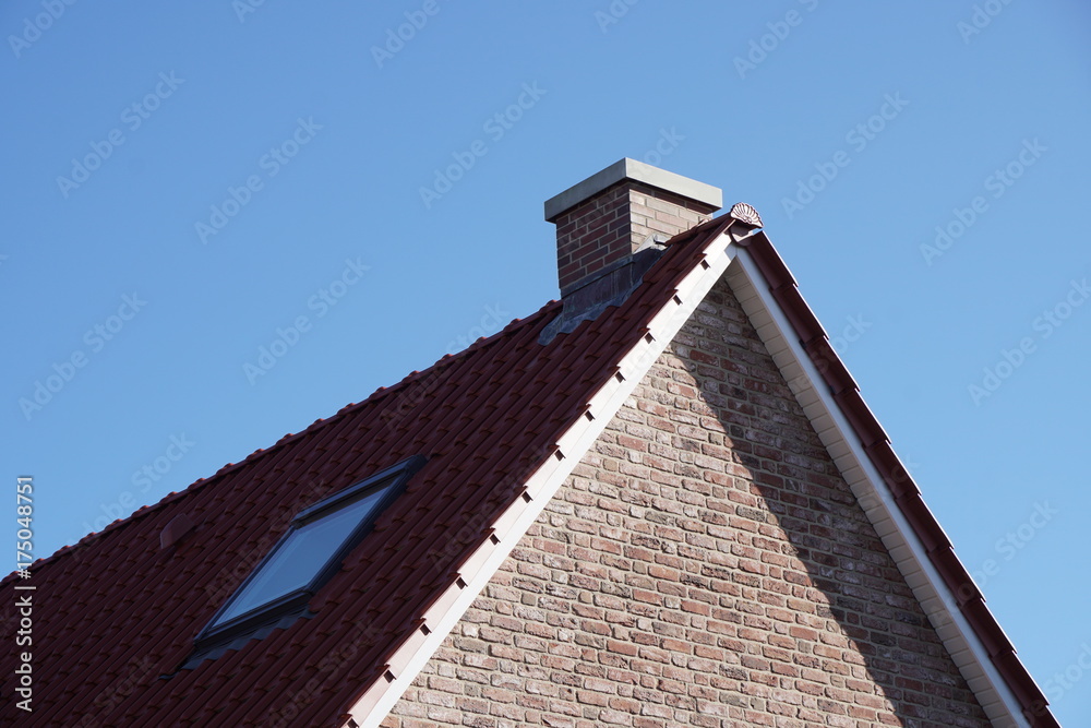 Schornstein auf einem Dach mit Dachpfannen und Fenster