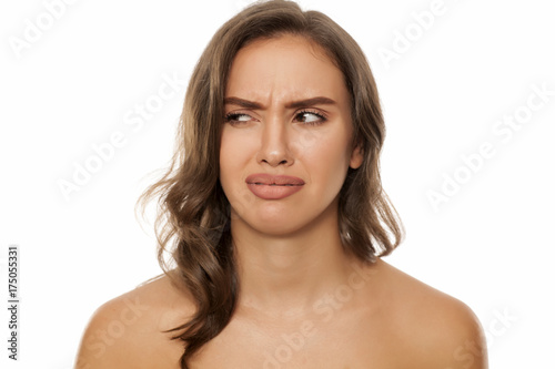Portrait of beautiful young disgusted woman on white background