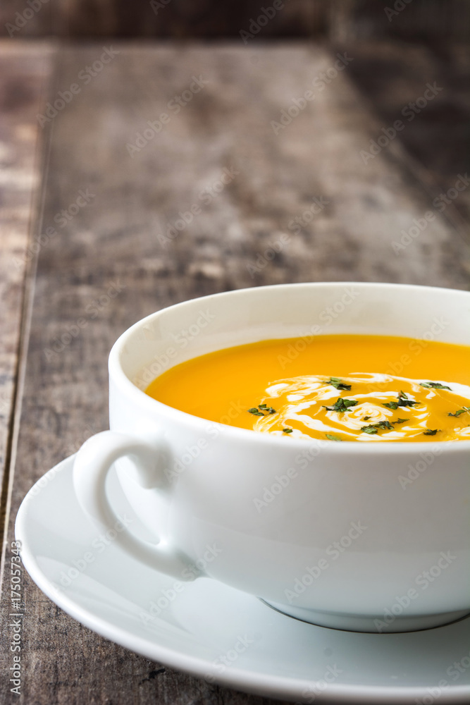 Pumpkin soup in white bowl on wooden table Pumpkin soup in white bowl on wooden table
