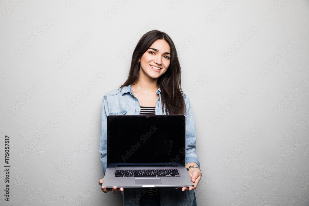 Portrait of a cheerful smiling girl in hat showing blank screen laptop isolated over gray background Portrait of a cheerful smiling girl in hat showing blank screen laptop isolated over gray background