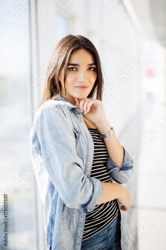 Young beauty woman hands on chin standing against panoramic windows