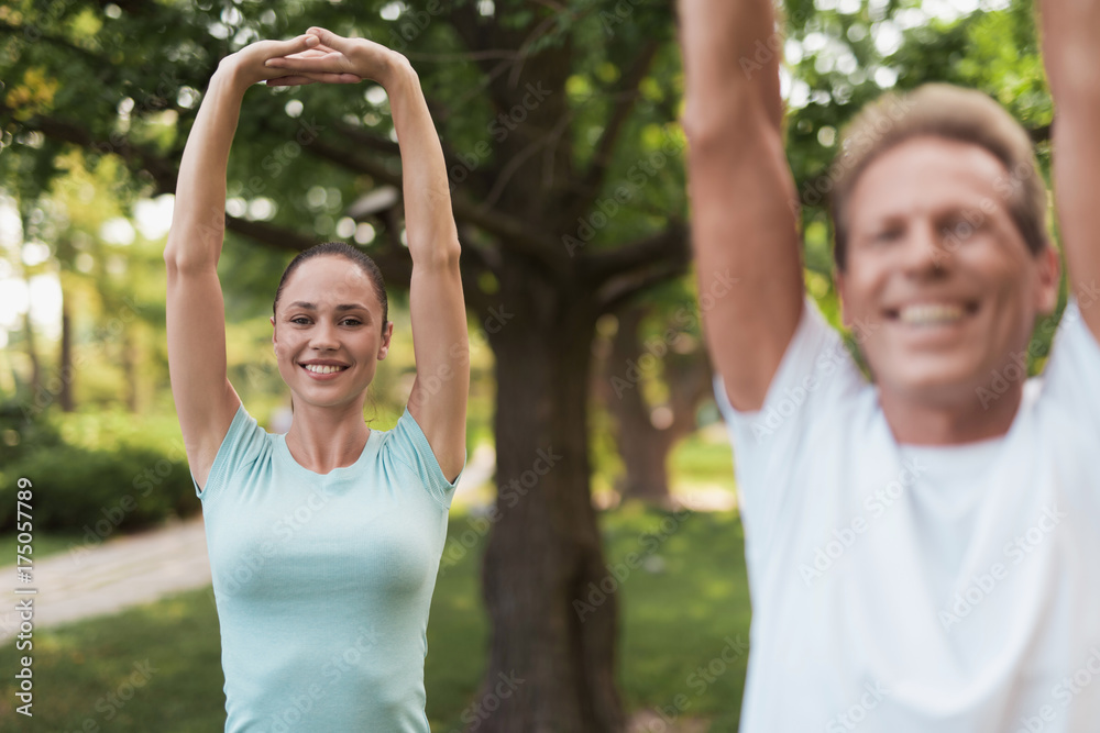 Couple doing exercises in the park. They do stretching hands Couple doing exercises in the park. They do stretching hands