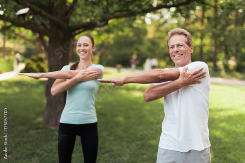 Man and woman doing exercises in the park. They warm up