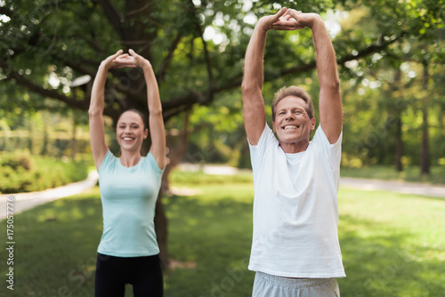 Couple doing exercises in the park. They do stretching hands