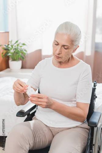 woman in wheelchair taking medicine © LIGHTFIELD STUDIOS