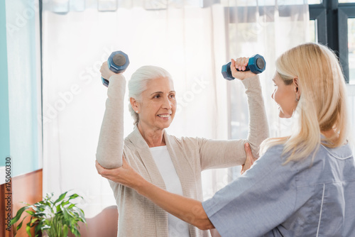 nurse and senior woman with dumbbells