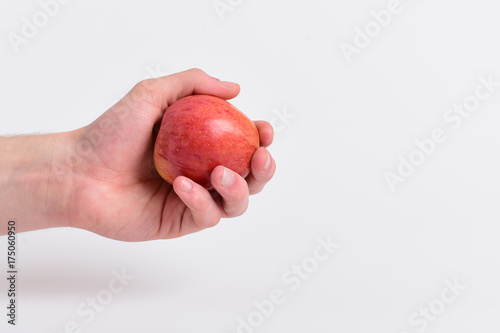 Fototapeta Naklejka Na Ścianę i Meble -  Male hand holds light red apple. Apple on light background