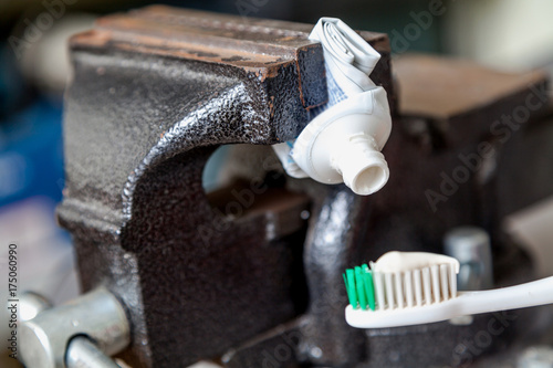 Toothpaste squeezed from tube onto brush squeezed vise