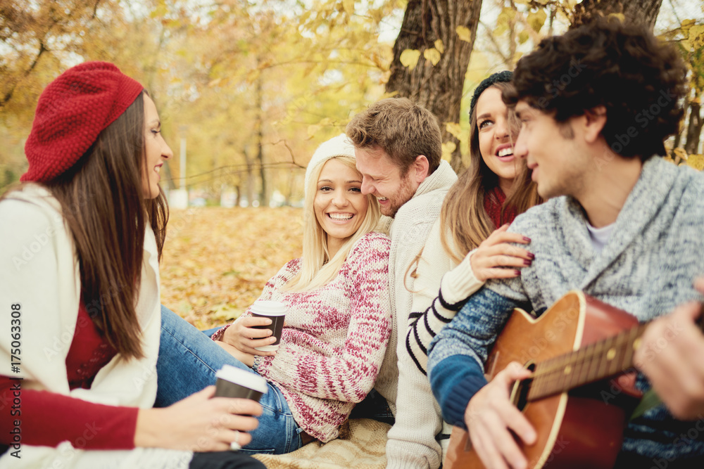 Friends having a good time in park at autumn/ singing and playing guitar Friends having a good time in park at autumn/ singing and playing guitar