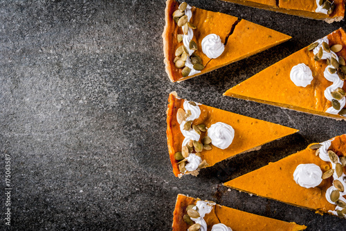 Traditional autumn dishes. Halloween, Thanksgiving. Set of cuted pieces of spicy pumpkin pie with whipped cream & pumpkin seeds on black stone table. Copy space top view