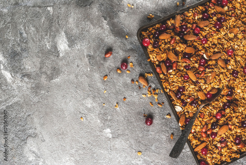 Ideas for a winter  autumn breakfast. Thanksgiving  Christmas. Homemade fresh cooked honey granola with nuts  almonds  peanuts  hazelnuts  and cranberries. On gray concrete table  Copy space top view