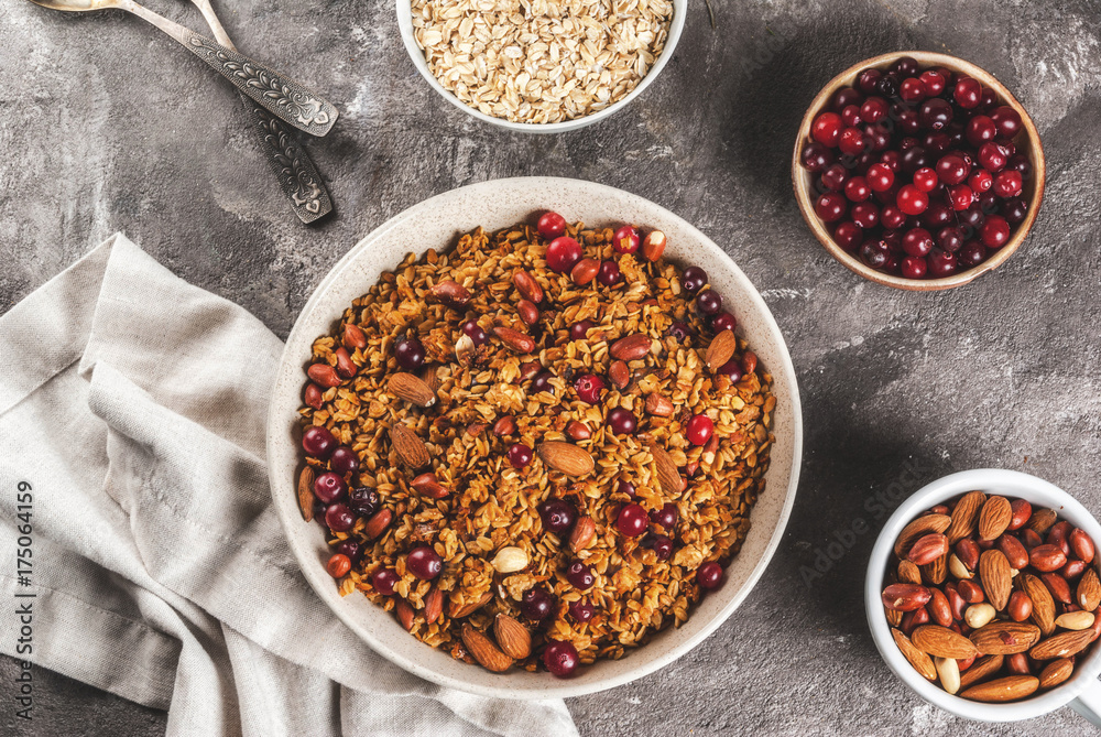 Ideas for a winter, autumn breakfast. Thanksgiving, Christmas. Homemade fresh cooked honey granola with nuts (almonds, peanuts, hazelnuts) and cranberries. On gray concrete table, Copy space top view Ideas for a winter, autumn breakfast. Thanksgiving, Christmas. Homemade fresh cooked honey granola with nuts (almonds, peanuts, hazelnuts) and cranberries. On gray concrete table, Copy space top view