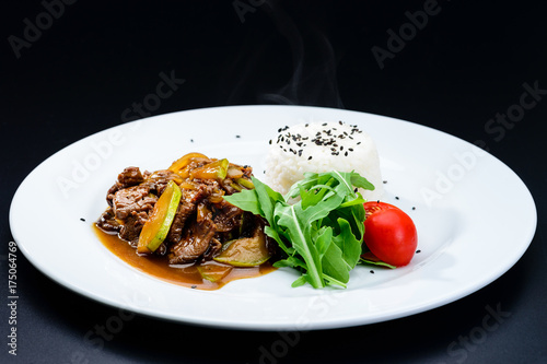 Delicious beef with oyster Mushrooms and rice served with tomatoes and sauce in a white plate, isolated on black background. Autumn menu in an Italian restaurant. Hotel service photo background