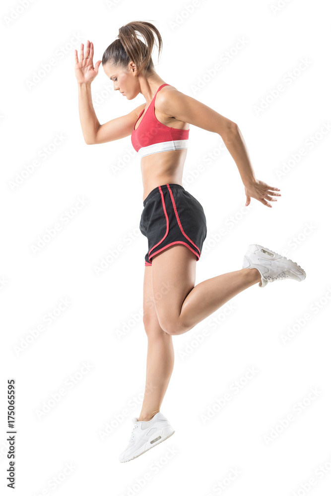 Side view of sporty focused confident fitness woman jumping movement. Full body length portrait isolated on white studio background. Side view of sporty focused confident fitness woman jumping movement. Full body length portrait isolated on white studio background.