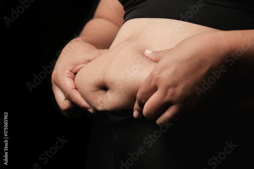 Woman is worried about belly fat. © amornchaijj