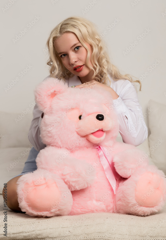 Happy beautiful blonde woman hugging a teddy bear. Concept of holiday or birthday