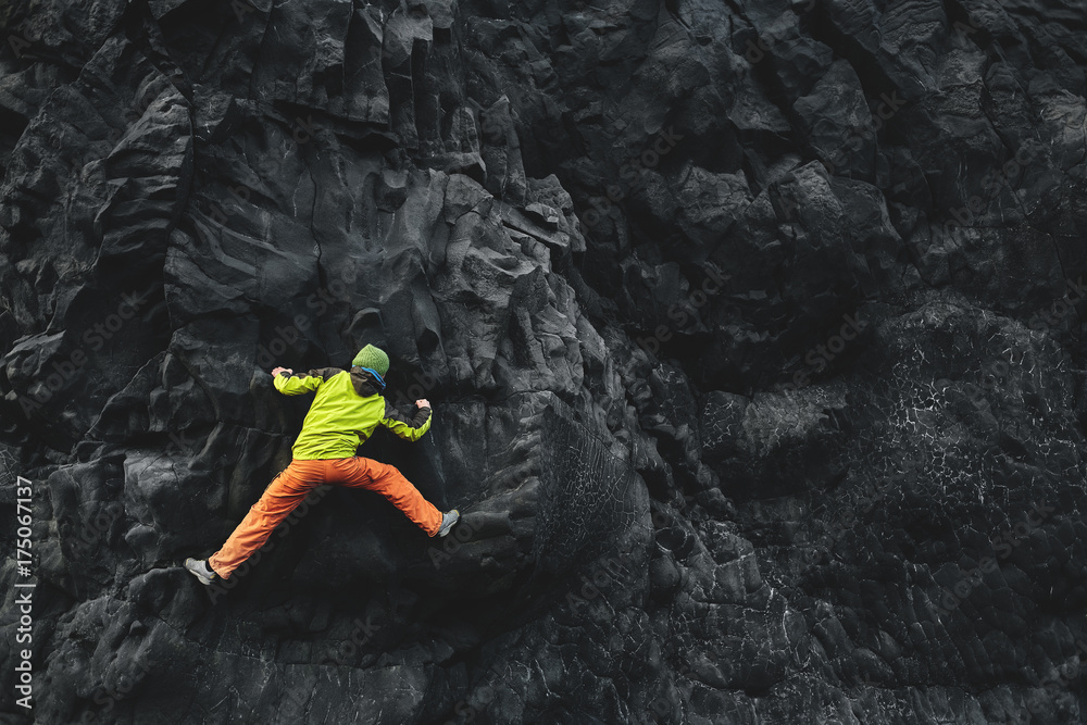male rock climber. rock climber climbs on a black rocky wall on the ocean bank in Iceland, Kirkjufjara beach. man makes hard move without rope. male rock climber. rock climber climbs on a black rocky wall on the ocean bank in Iceland, Kirkjufjara beach. man makes hard move without rope.