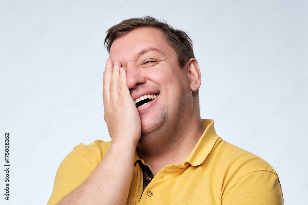 Caucasian fat man laughs and covers his face with his hands. Caucasian fat man laughs and covers his face with his hands.