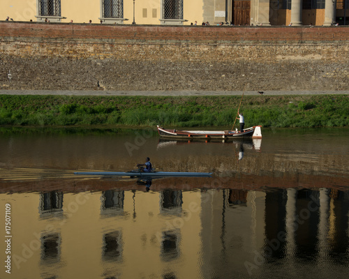 Boats from different millennia pass each other on the River Arno in Florence, Italy