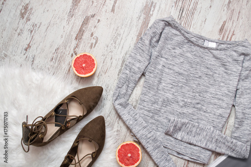 Gray sweater on a wooden background, brown shoes, half a grapefruit. Fashionable concept